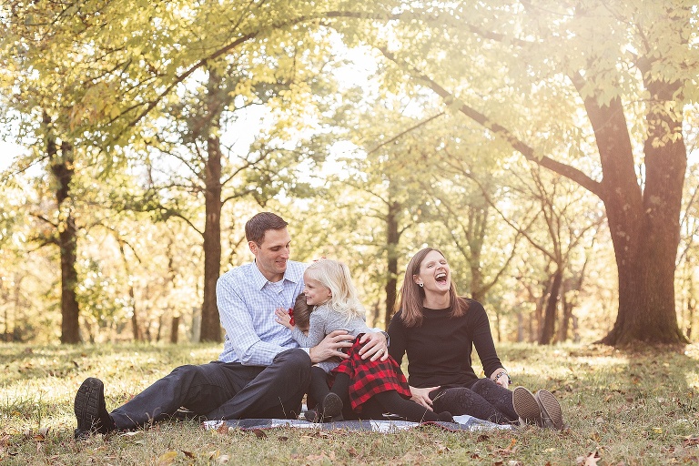 Kids hugging and mom laughing while sitting on blanket in park on fall evening | St. Louis Photography