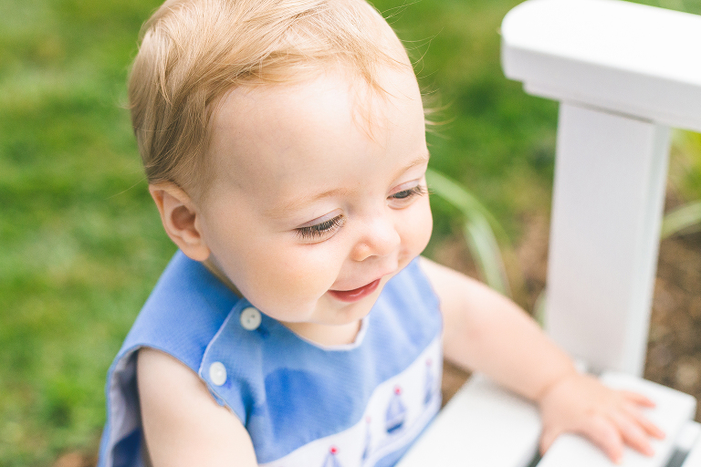 Sweet little boy standing up and holding onto white bench. | St. Louis Photographer