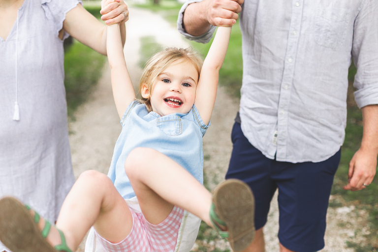 Mom and dad holding daughter's hands and swinging in Faust Park | St Louis Photographer